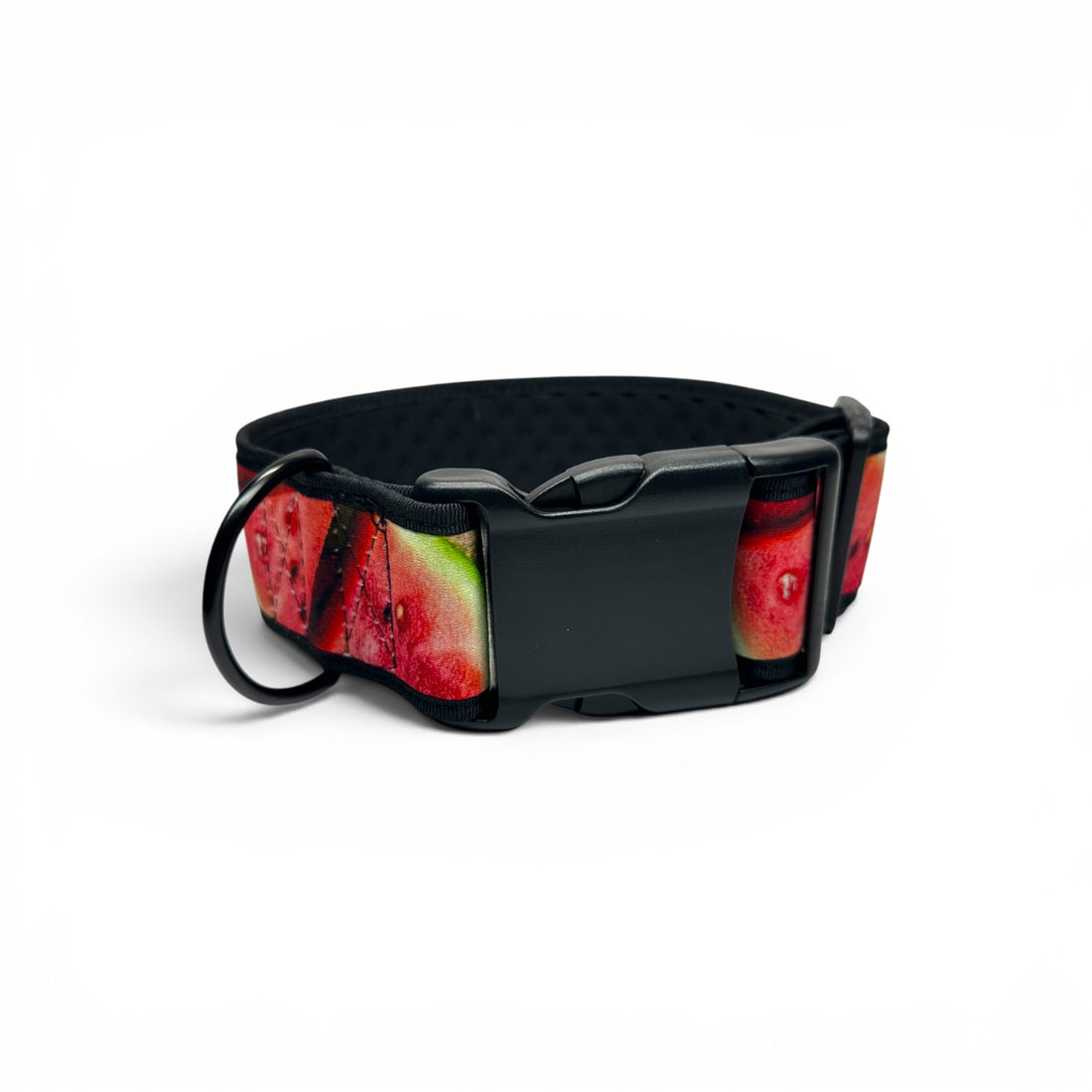 A black pet collar featuring a vibrant watermelon slice pattern with red flesh, green rinds, and black seeds, complete with a black plastic buckle and a matching black ring attachment.